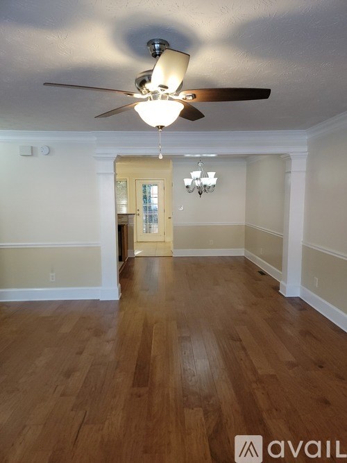 A room with a ceiling fan and wooden flooring.