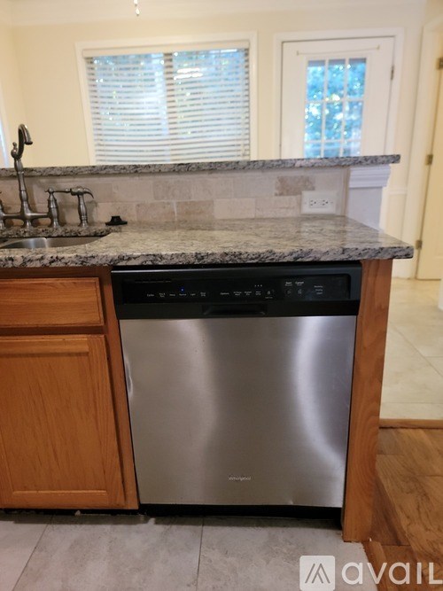A kitchen with a granite countertop and a stainless steel dishwasher.