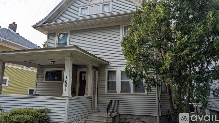 A house with a porch and a tree in front.