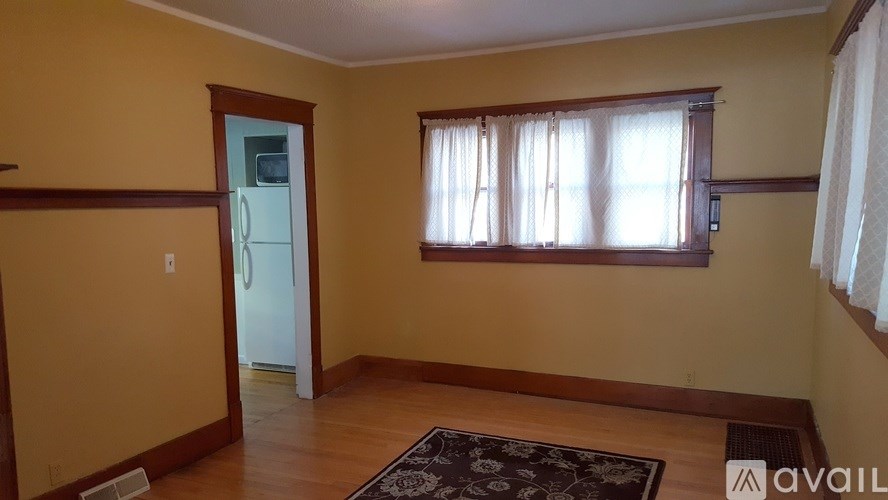 A room with a rug on the floor and a window with curtains.