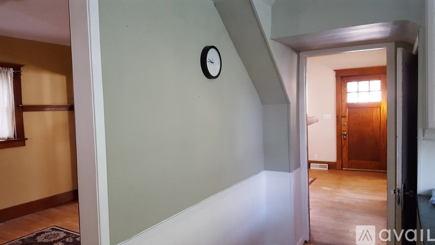 A hallway with a clock on the wall and a door at the end.