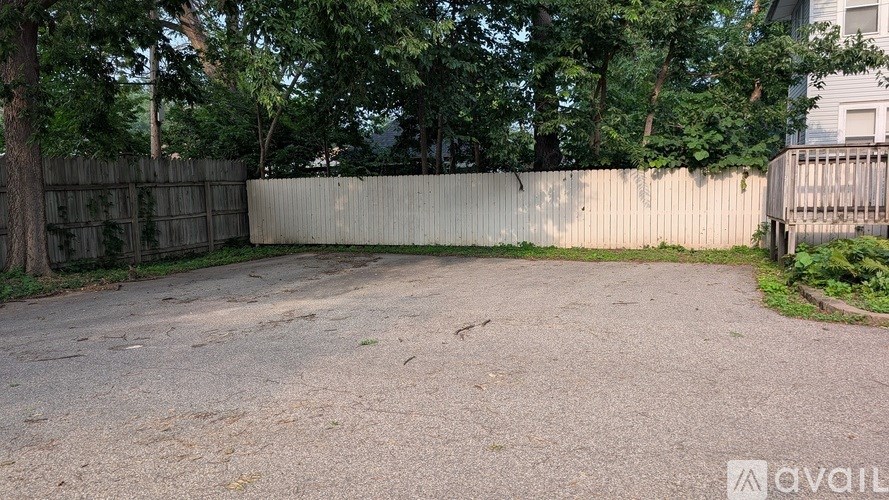 A backyard with a wooden fence and a gravel driveway.