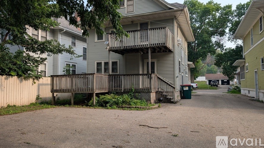 A two-story house with a balcony and a driveway in front.