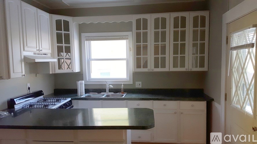 A kitchen with white cabinets and a black countertop.