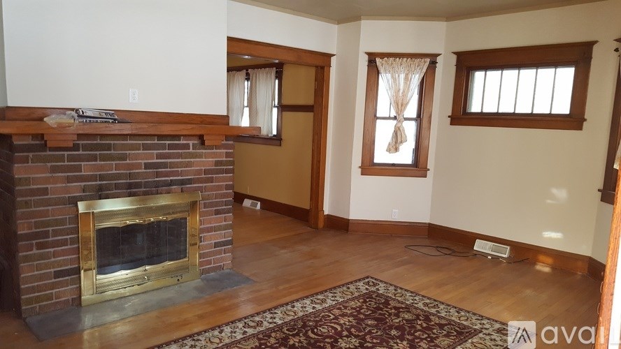 A living room with a fireplace and a rug in front of it.