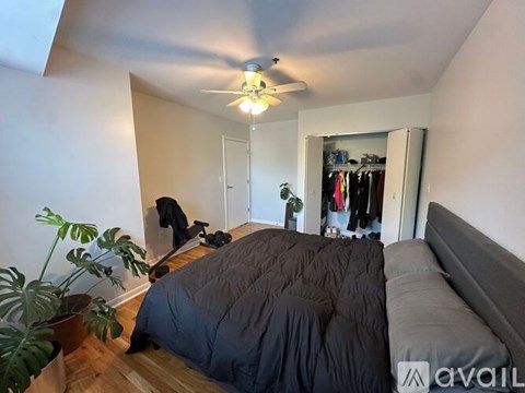 A bedroom with a bed, a ceiling fan, and a wardrobe.