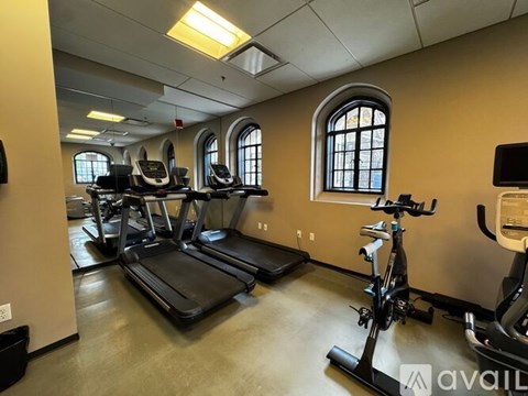 A gym with treadmills, elliptical machines, and a television.
