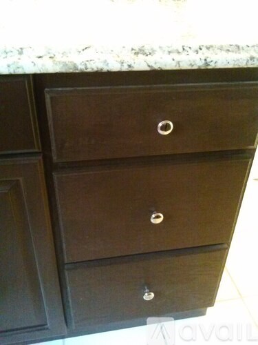 A brown drawer with a silver handle is in front of a cabinet.