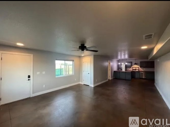 A spacious room with a ceiling fan and a large window.
