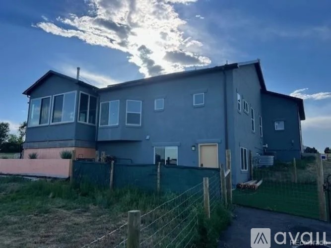 A grey house with a fence in front of it.