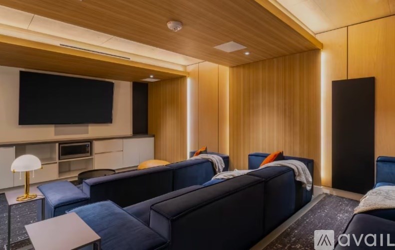 A modern living room with a dark blue sofa set and a wooden ceiling.