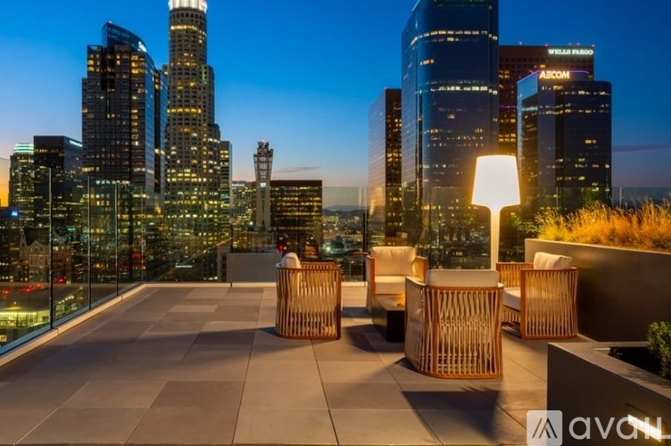 A rooftop patio with chairs and a city skyline at dusk.