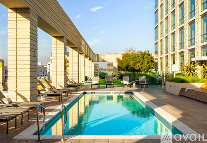 A pool surrounded by lounge chairs and a building in the background.