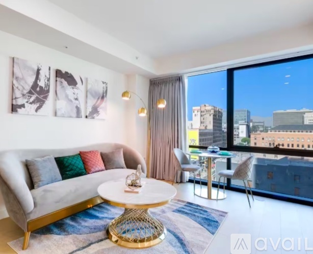 A living room with a white couch and a round table with a gold base.