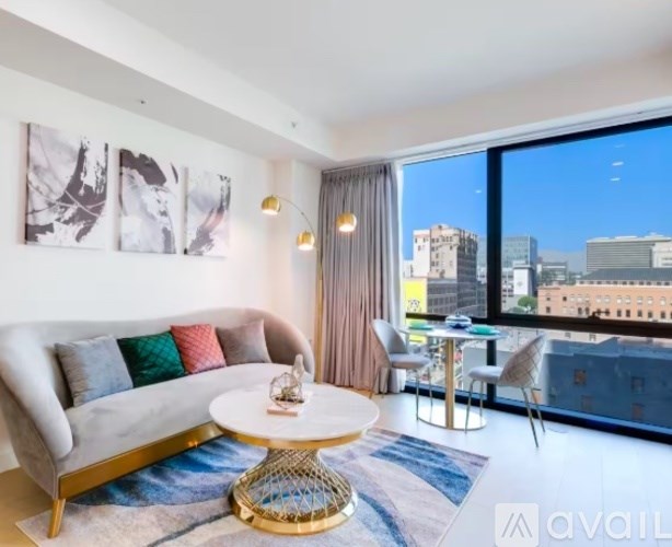 A living room with a white couch and a round table with a gold base.