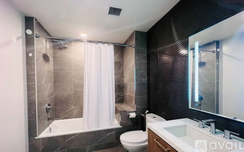 A modern bathroom with a white toilet, a white sink, and a glass shower enclosure.