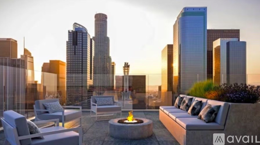 A patio with a fire pit and seating area overlooking a city skyline at dusk.