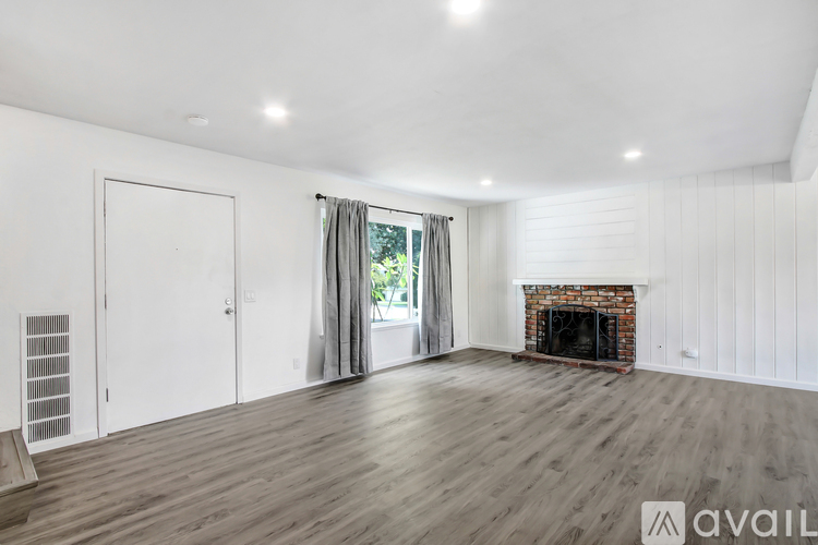 A spacious room with a fireplace and wooden flooring.
