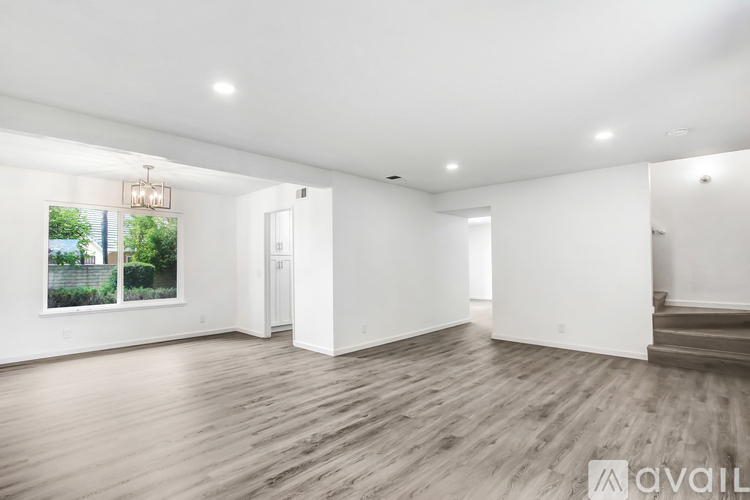 A spacious room with wooden flooring and white walls.
