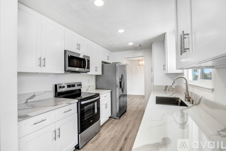 A modern kitchen with white cabinets and stainless steel appliances.