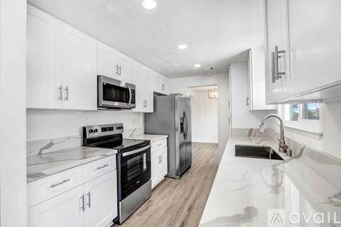 A modern kitchen with white cabinets and stainless steel appliances.