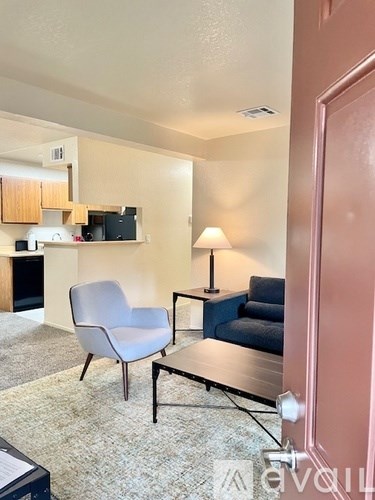 A living room with a grey chair, a blue couch, and a black coffee table.