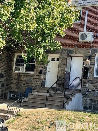 A house with a white door and a tree in front.