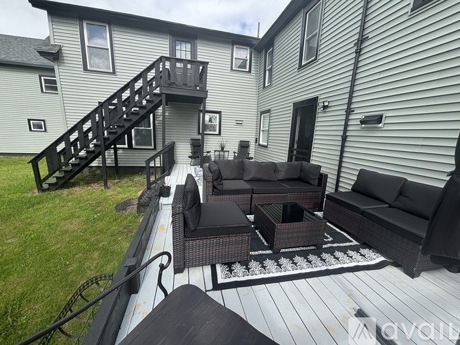 A patio with a black couch, chairs, and a table.
