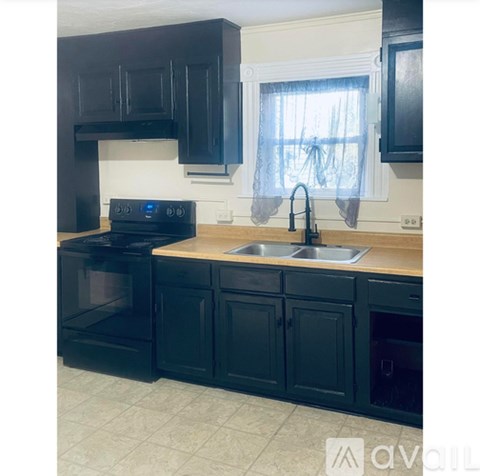 A kitchen with black cabinets and a wooden countertop.