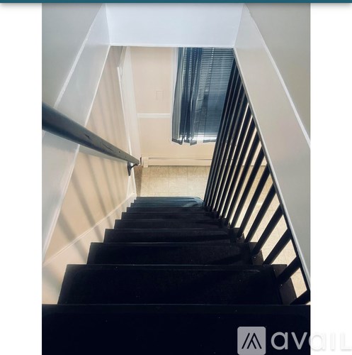 A staircase with a black carpeted runner and white walls.