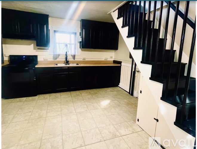 A kitchen with black cabinets and a white sink.