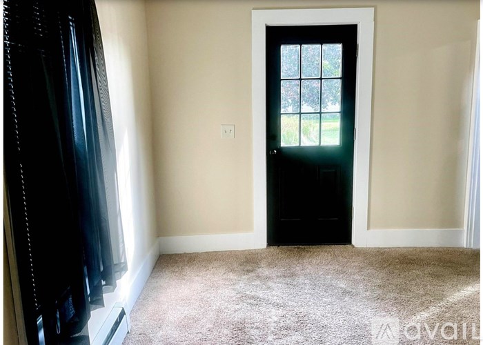 A room with a black door and carpeted floor.