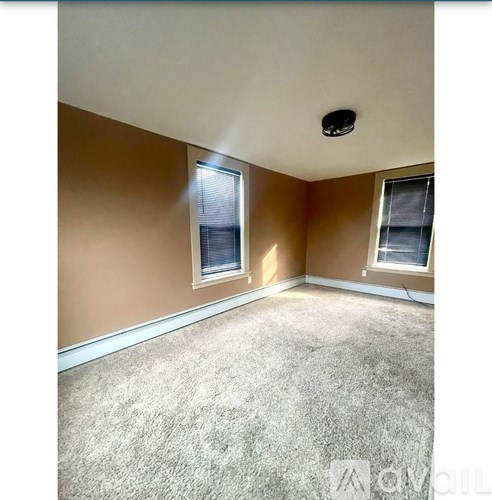 A room with a carpeted floor and two windows.
