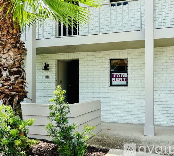 A white building with a FOR RENT sign on the window.