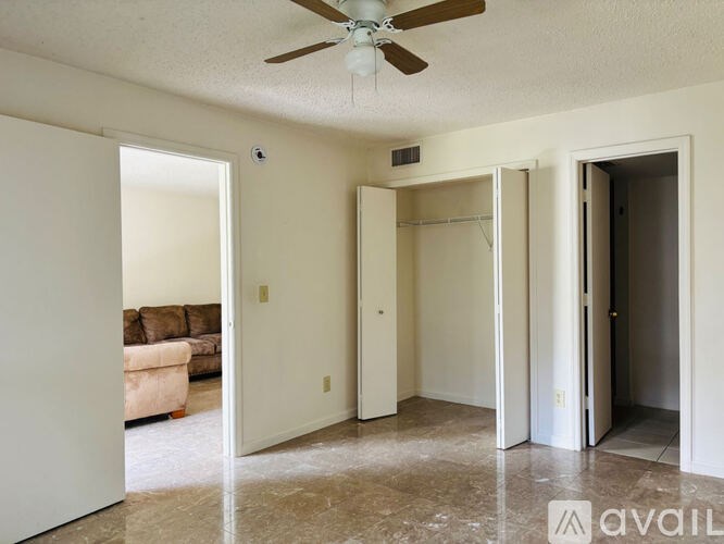 A room with a ceiling fan and a couch in the background.