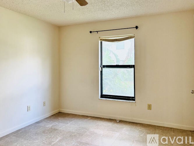 A room with a window and a fan on the ceiling.
