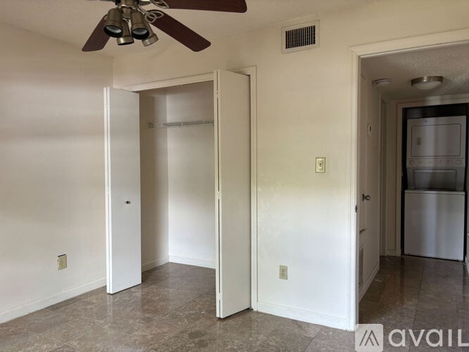 A room with a ceiling fan and a refrigerator in the corner.
