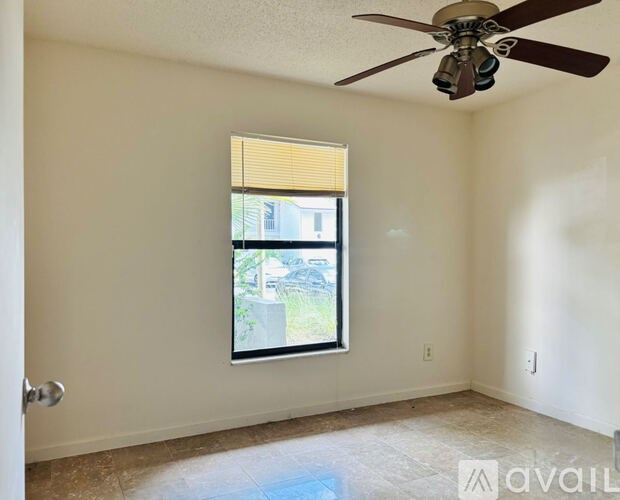 A room with a ceiling fan and a window with blinds.