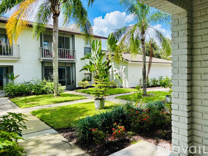 A white building with a balcony and a green lawn in front.