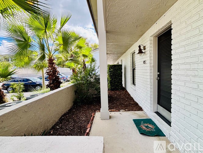 A white house with a black door and a green mat on the porch.