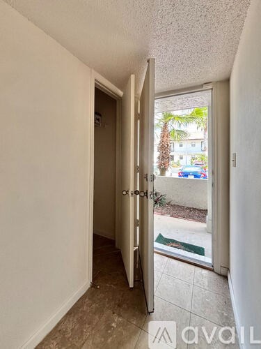 A white door is open to a balcony with a view of a pool and a house.