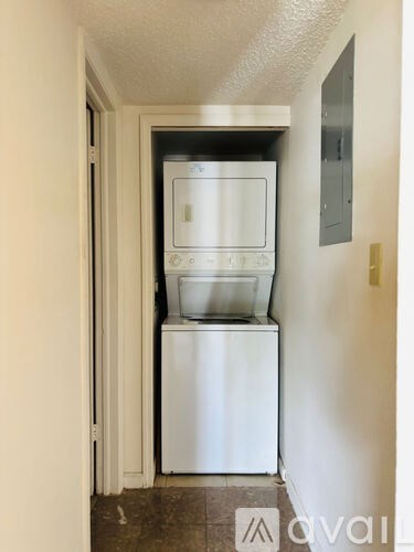 A white dishwasher and microwave are stacked on top of each other in a narrow hallway.