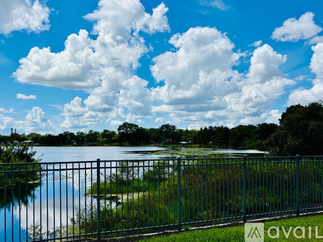 A fence surrounds a body of water with a cloudy sky above.