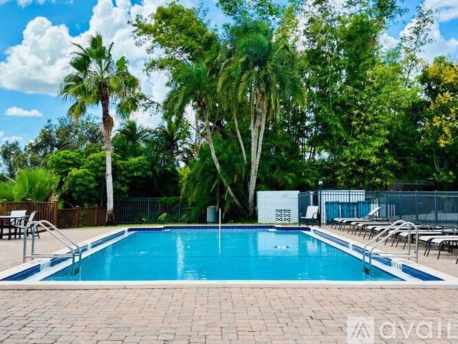 A pool surrounded by trees and chairs.