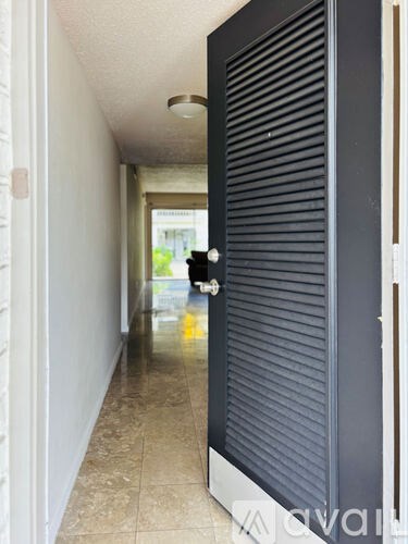 A hallway with a closed black door and a tiled floor.
