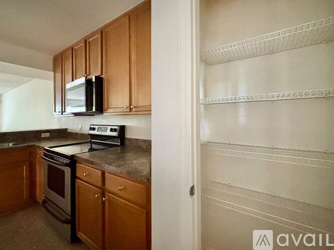 A kitchen with wooden cabinets and a black microwave above the stove.