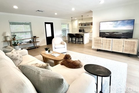 A living room with a white couch and a television on the wall.