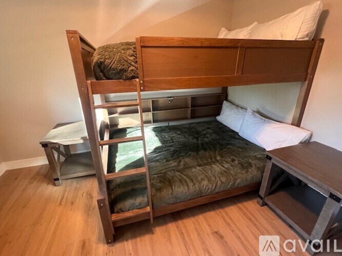 A wooden bunk bed with a green mattress and a white pillow on top.