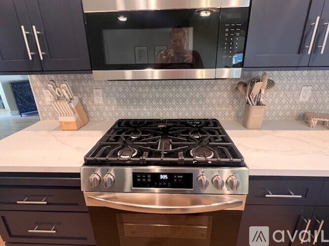A modern kitchen with a stove top oven and a person in the background.