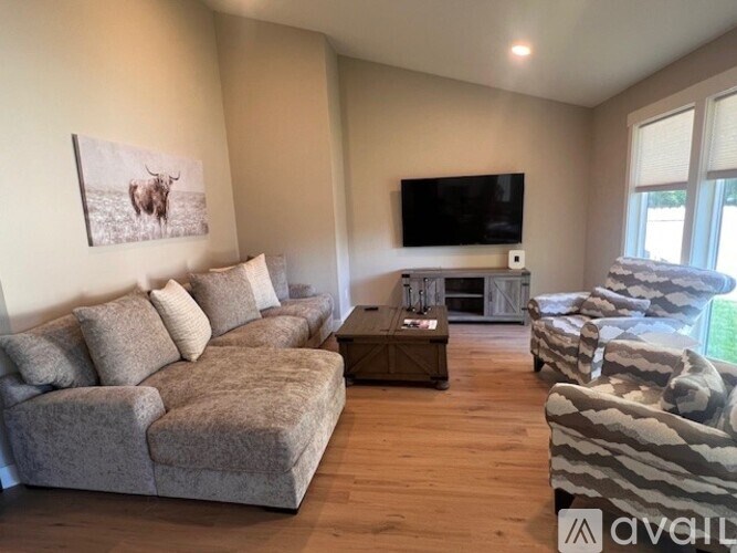 A living room with a grey couch, a wooden coffee table, and a television on the wall.